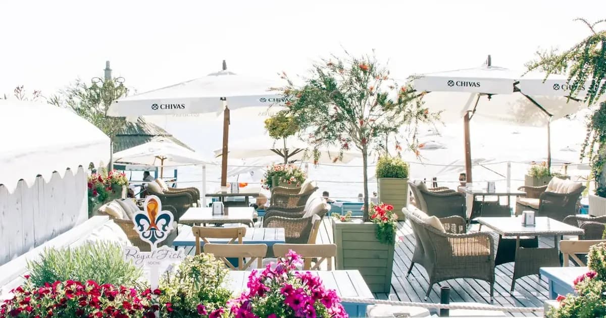 outdoor seaside restaurant terrace with white umbrellas and colorful flowers