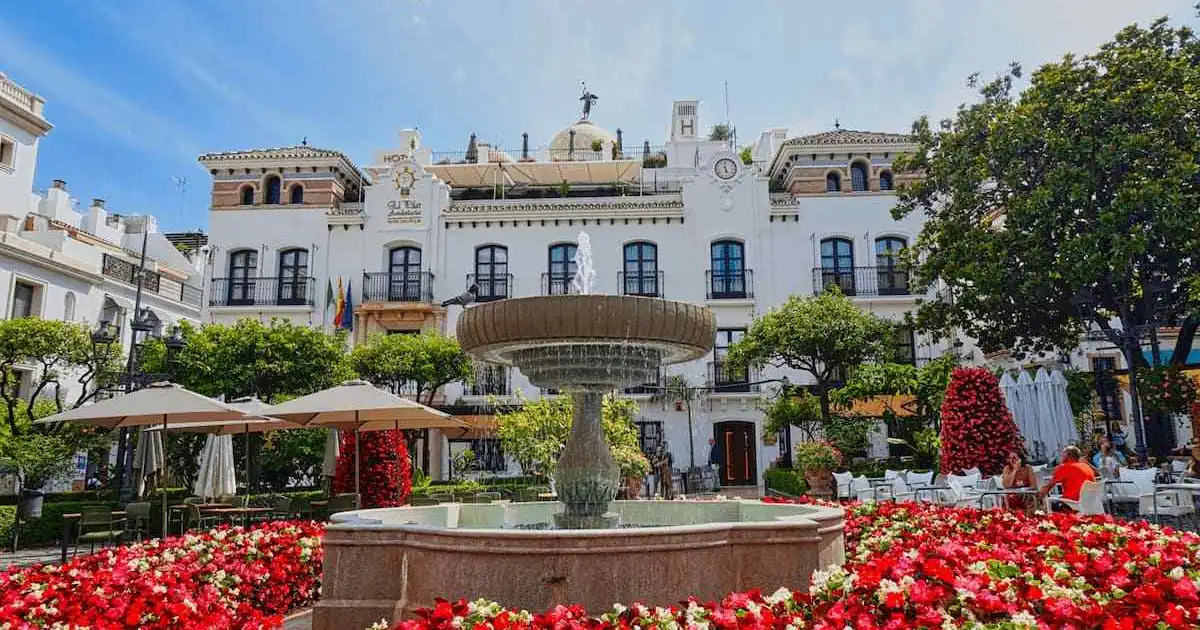Scenic view of a traditional white-washed street in Estepona old town with vibrant flower pots.