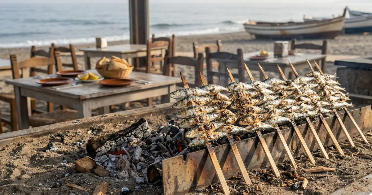 Traditional espetos de sardinas grilling over wood fire on Malaga beach chiringuito
