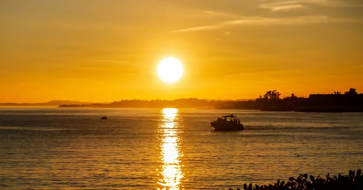 Sunset over the sea in Marbella, with golden sky reflections on the water and a motorboat cruising near the shore.