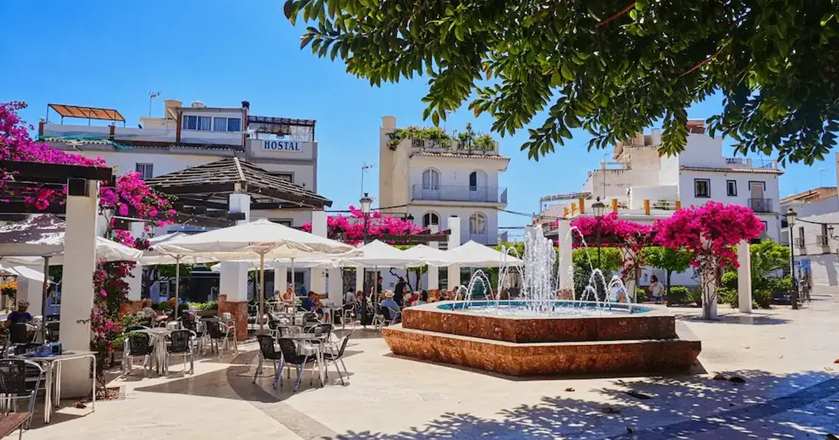 Relaxing outdoor cafe and beautiful fountain in a classic whitewashed square in Nerja, Andalusia