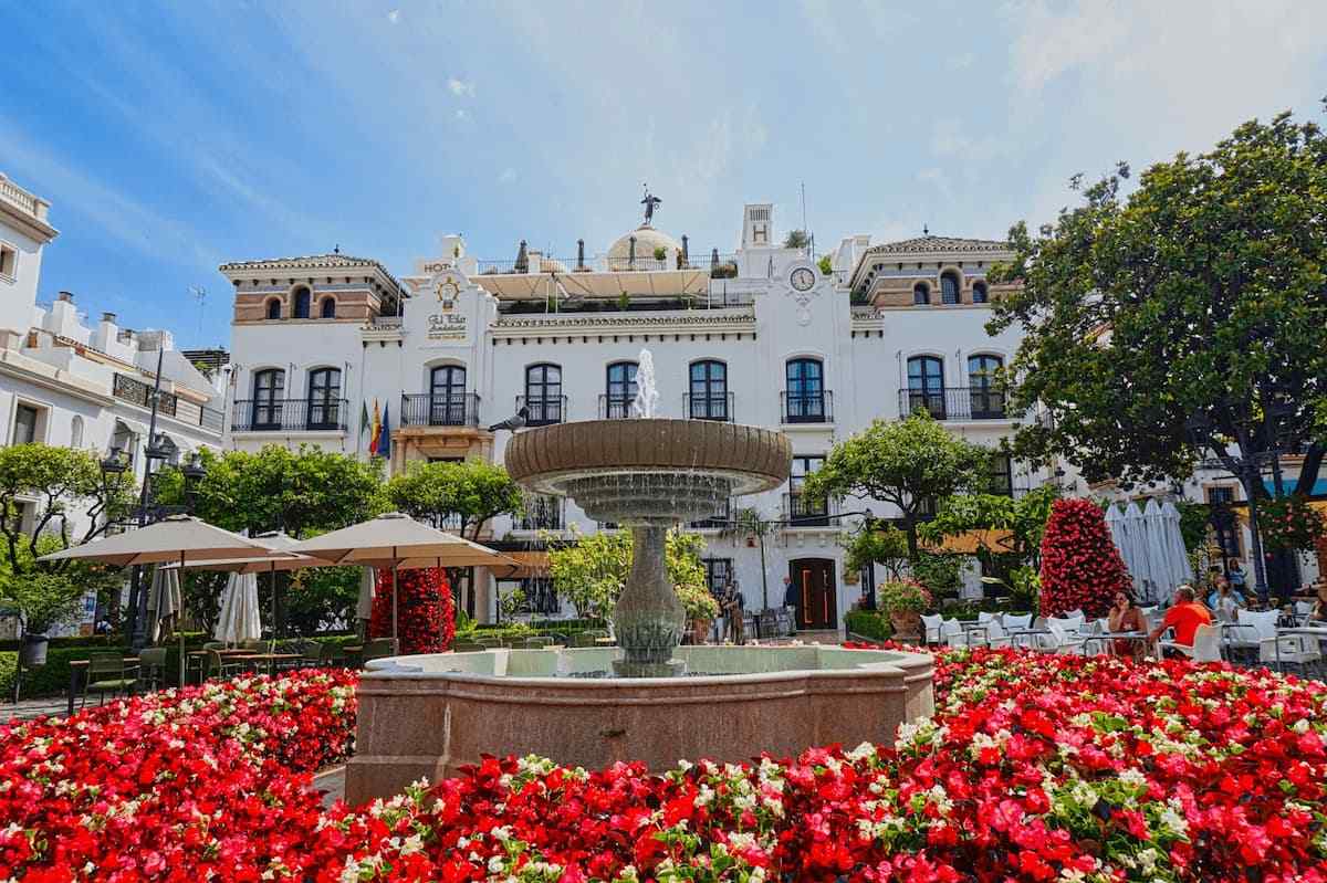 Scenic view of a traditional white-washed street in Estepona old town with vibrant flower pots.