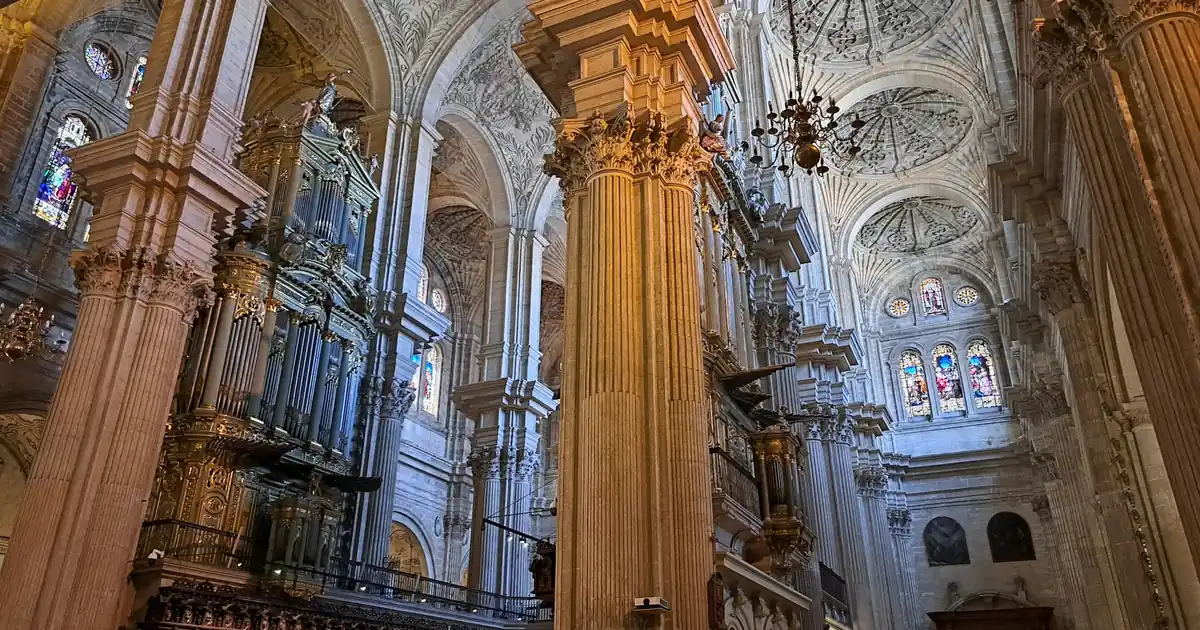 Malaga Cathedral (La Manquita) facade with its iconic single tower against a clear blue Andalusian sky.