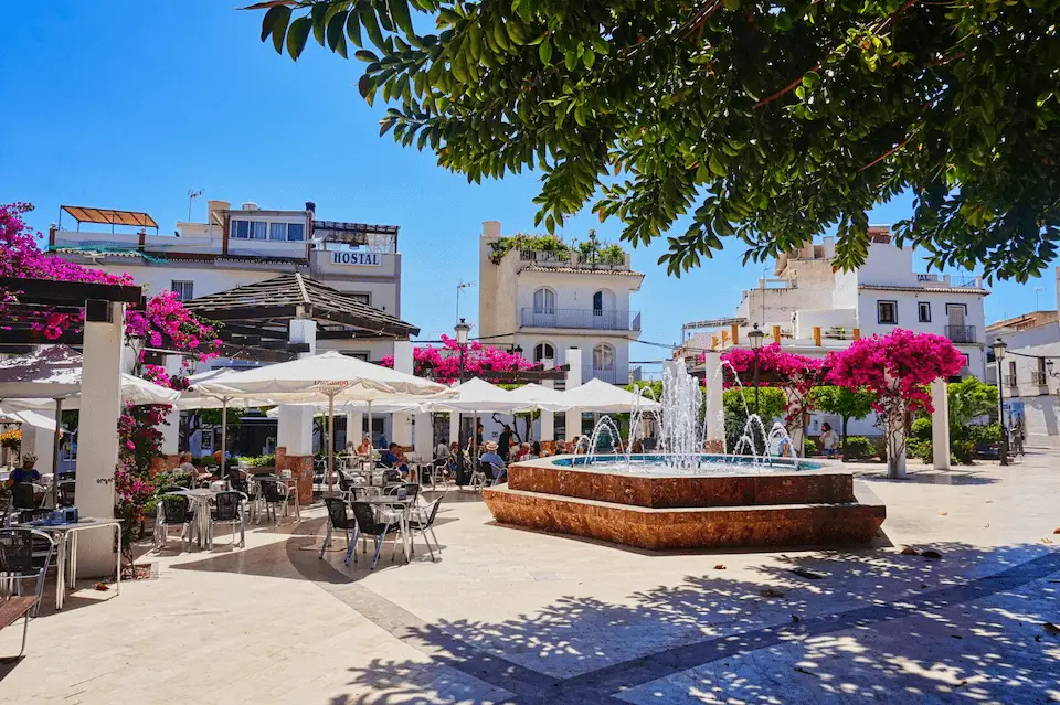 Relaxing outdoor cafe and beautiful fountain in a classic whitewashed square in Nerja, Andalusia