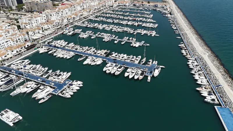 Luxury yachts docked in Puerto Banus marina with white Andalusian buildings and La Concha mountain in the background, Marbella, Spain.