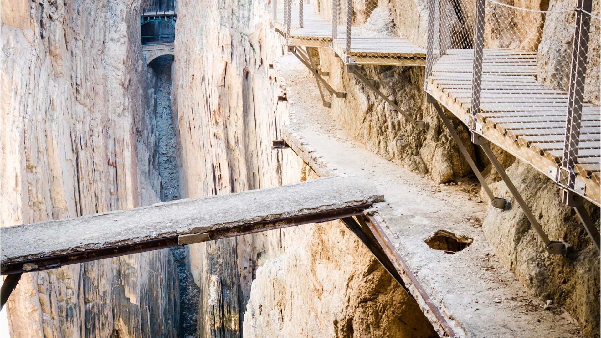 Narrow cliffside walkway and metal staircases along the rocky gorge on Caminito del Rey hiking trail in Malaga, Spain