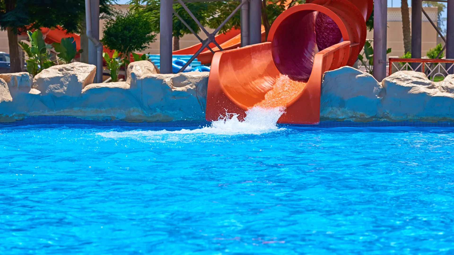 Water slide in Family resort splashing into a bright blue pool.