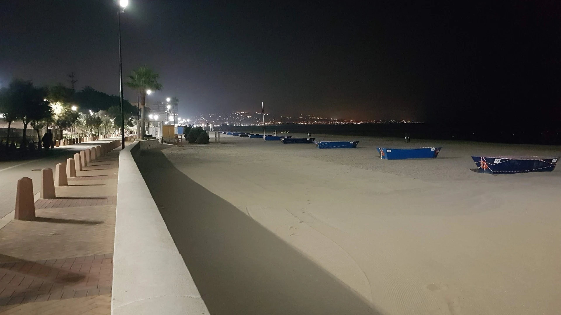 Fuengirola's seafront promenade lit up at night with the town lights across the bay