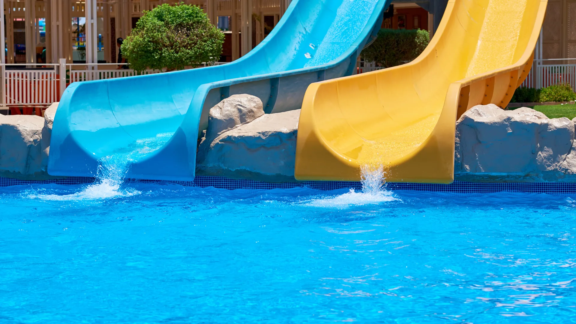 Blue and yellow water slides splashing into a bright pool at a family water park, perfect for kids on holiday