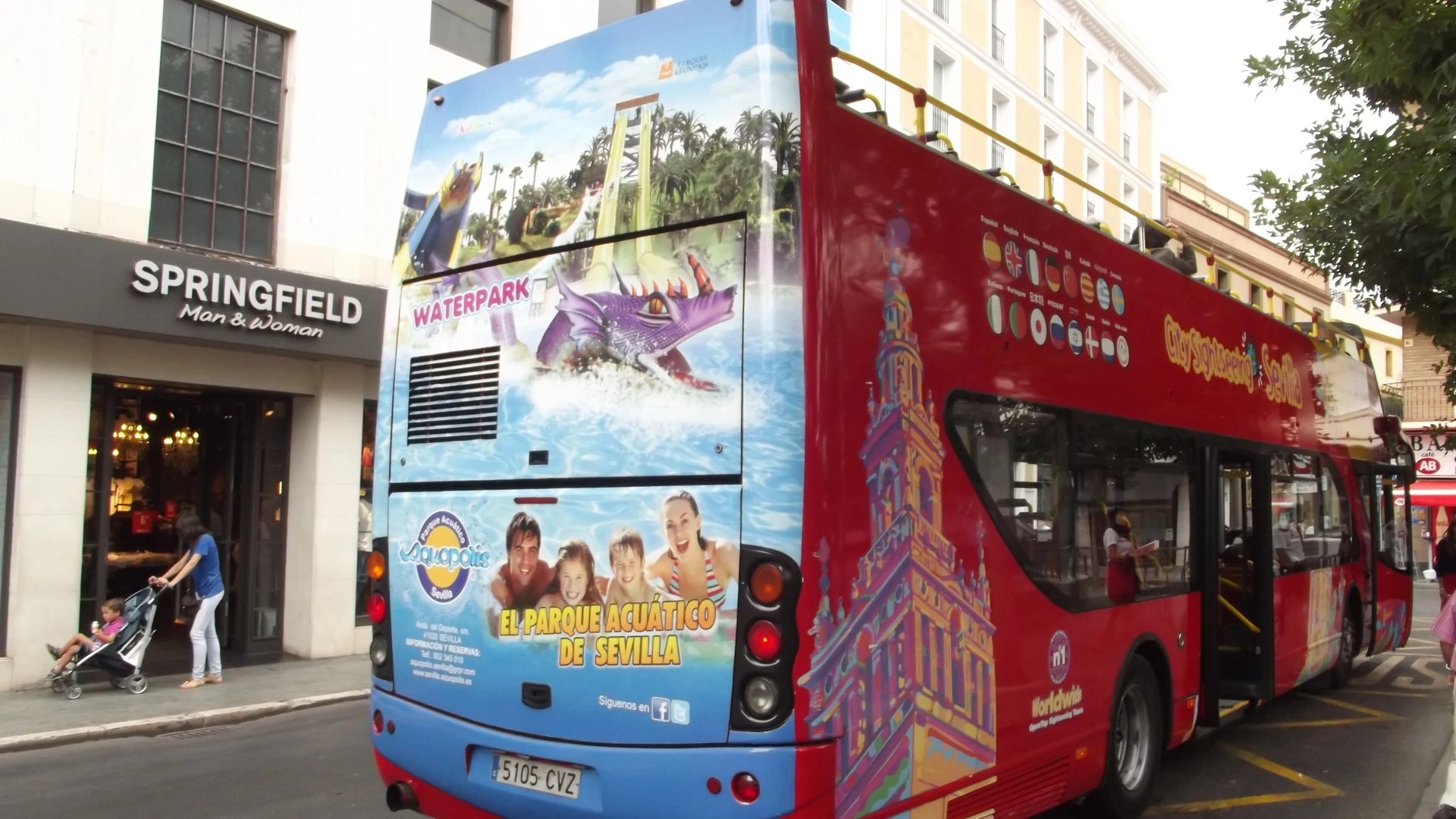 A City Sightseeing open-top double-decker bus in a Spanish city square