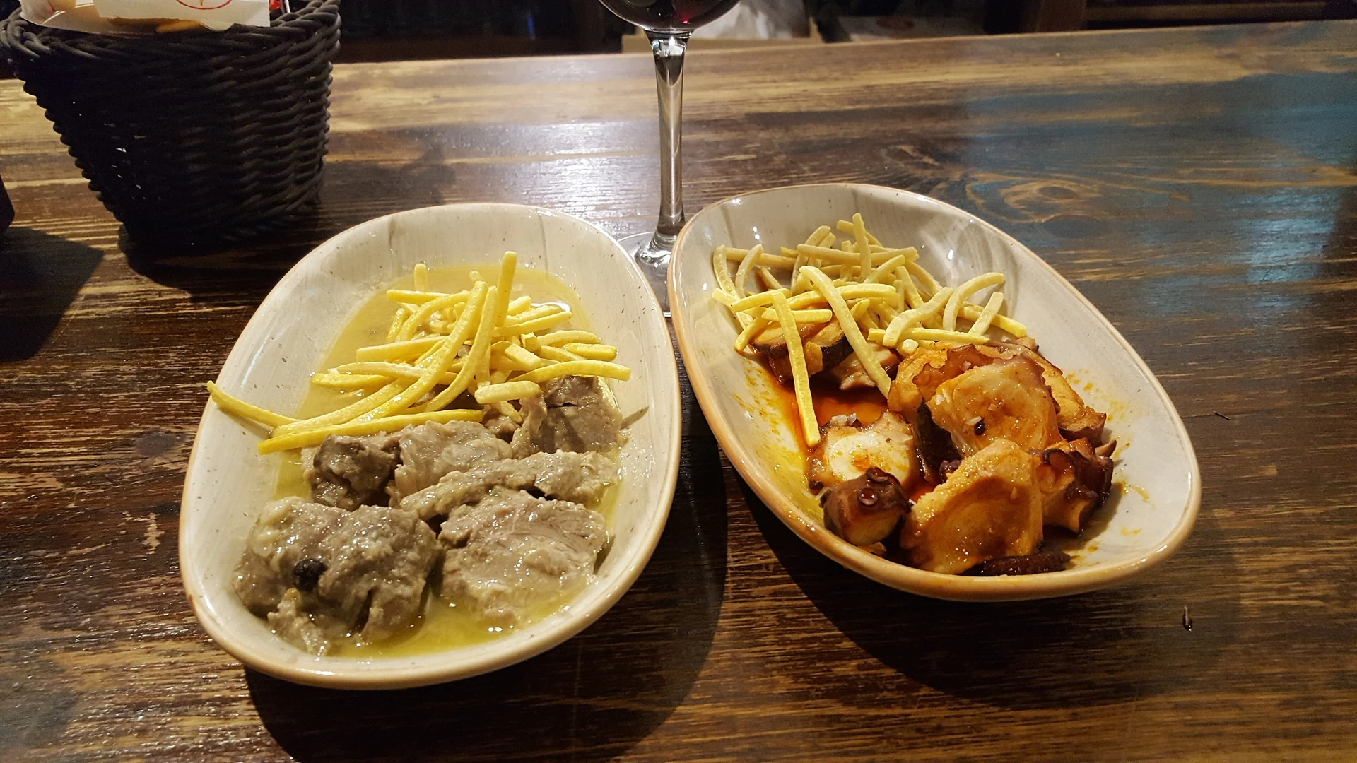 Tapas z ośmiornicą i mięsem oraz kieliszek wina w El Pimpi w Maladze.