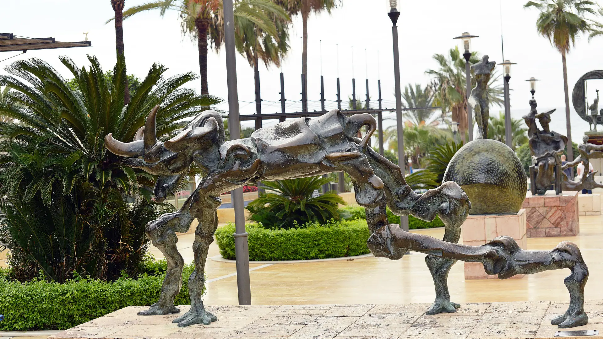 A Salvador Dalí bronze sculpture on Avenida del Mar in Marbella, lined with palm trees
