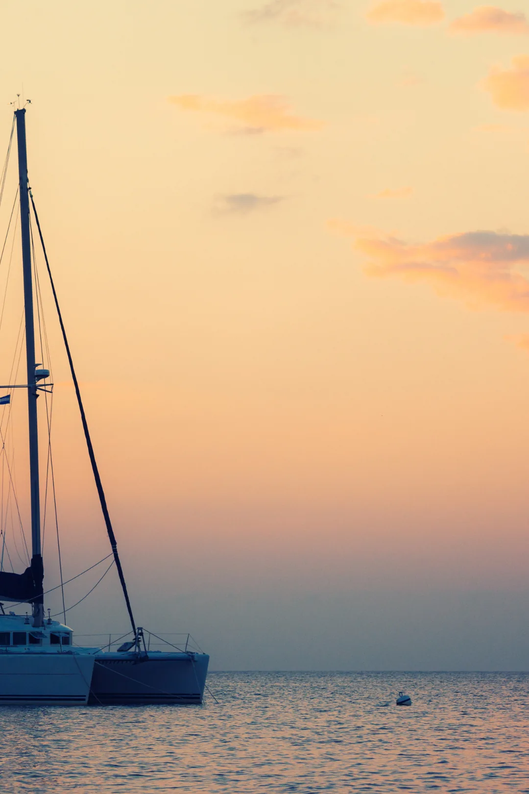 Catamaran sailboat silhouetted against a golden sunset sky on a calm sea during a boat trip from Fuengirola