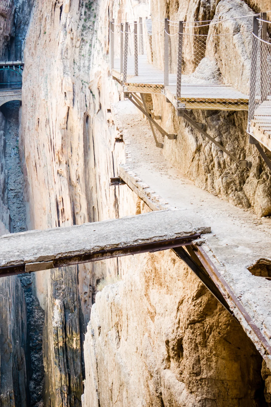 Narrow cliffside walkway and metal staircases along the rocky gorge on Caminito del Rey hiking trail in Malaga, Spain