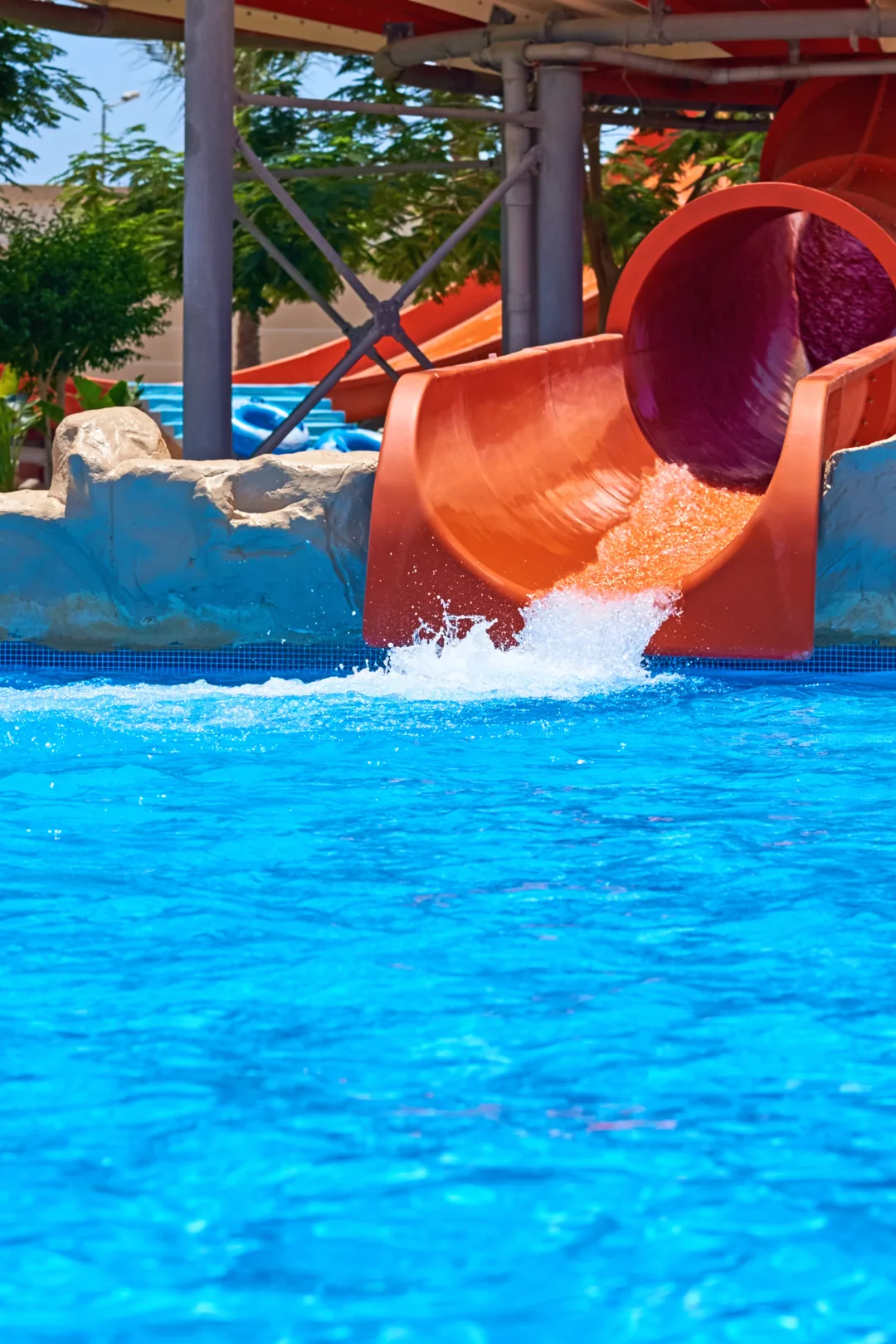 Water slide in Family resort splashing into a bright blue pool.