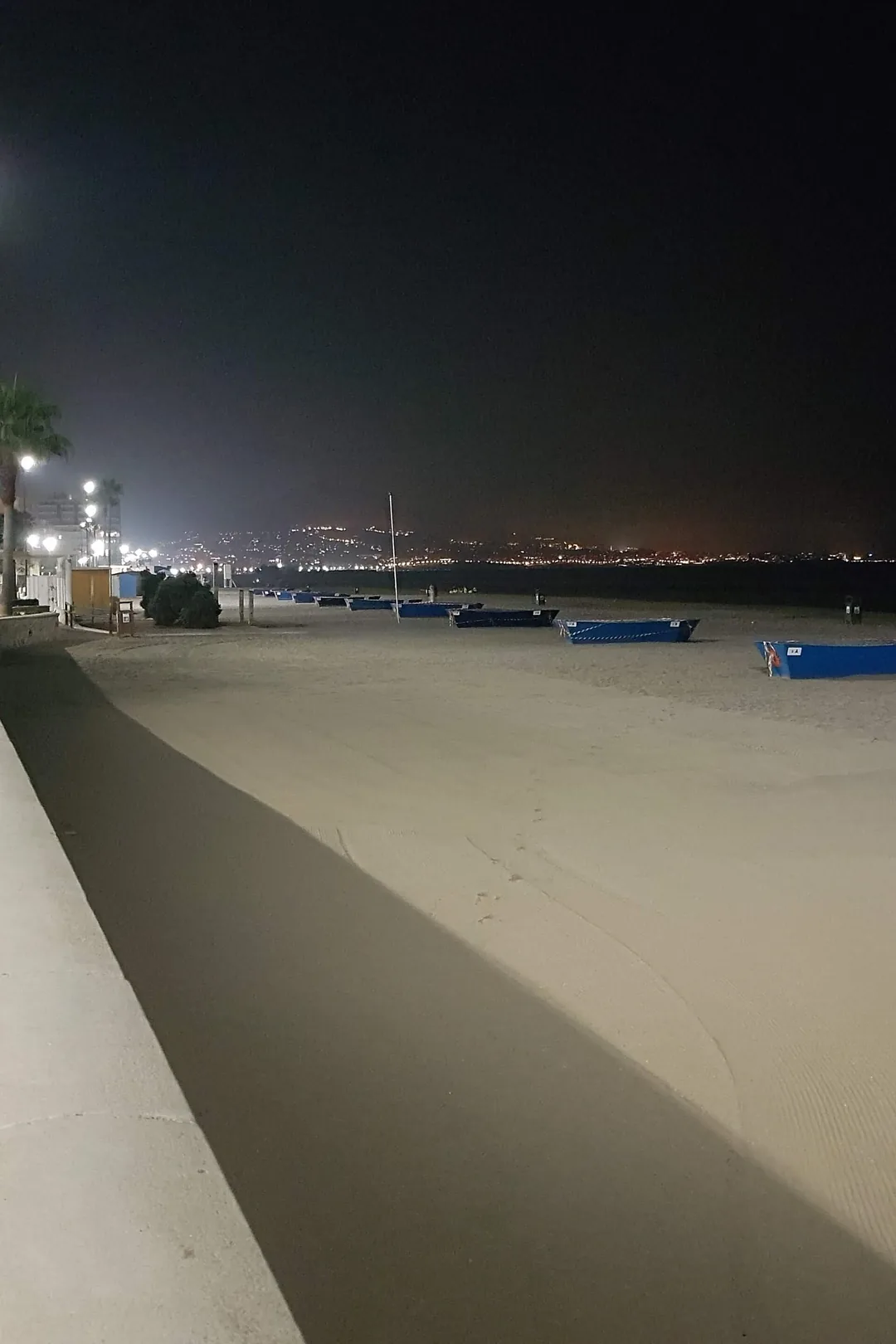 Fuengirola's seafront promenade lit up at night with the town lights across the bay