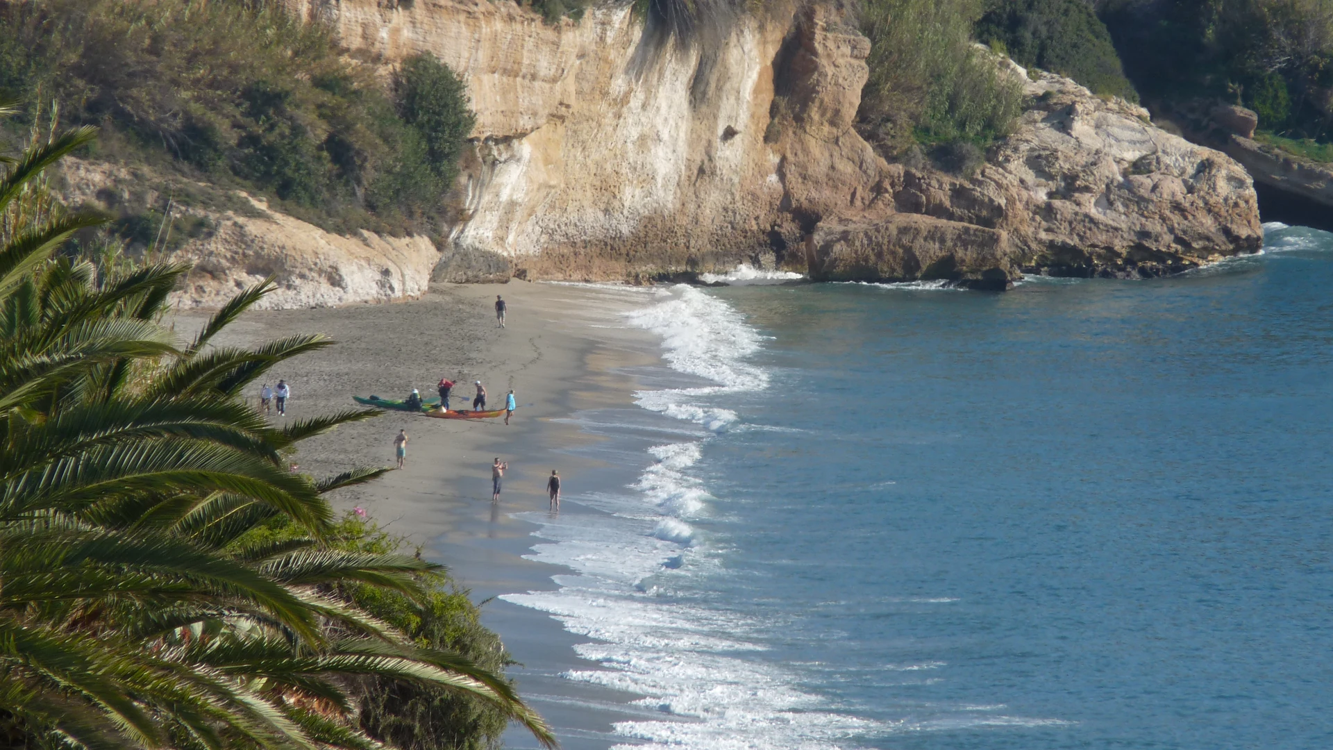 Burriana beach in Nerja with golden sand, sunbeds and clear Mediterranean water backed by the town