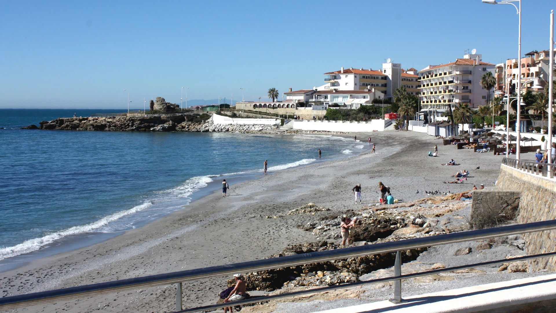 A calm sandy beach in Nerja with families and clear shallow water, ideal for children