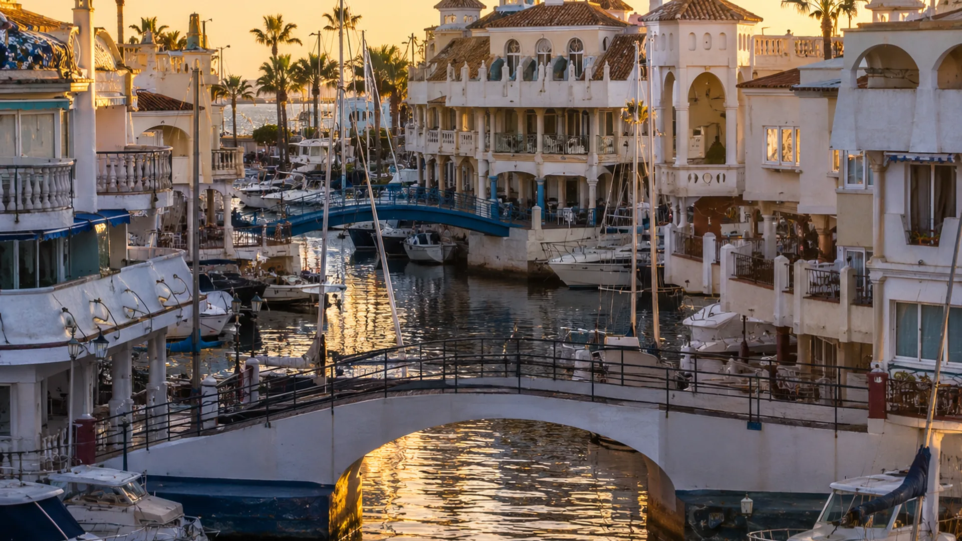 Puerto Marina Benalmádena canals with yachts and Mediterranean waterfront architecture at sunset.