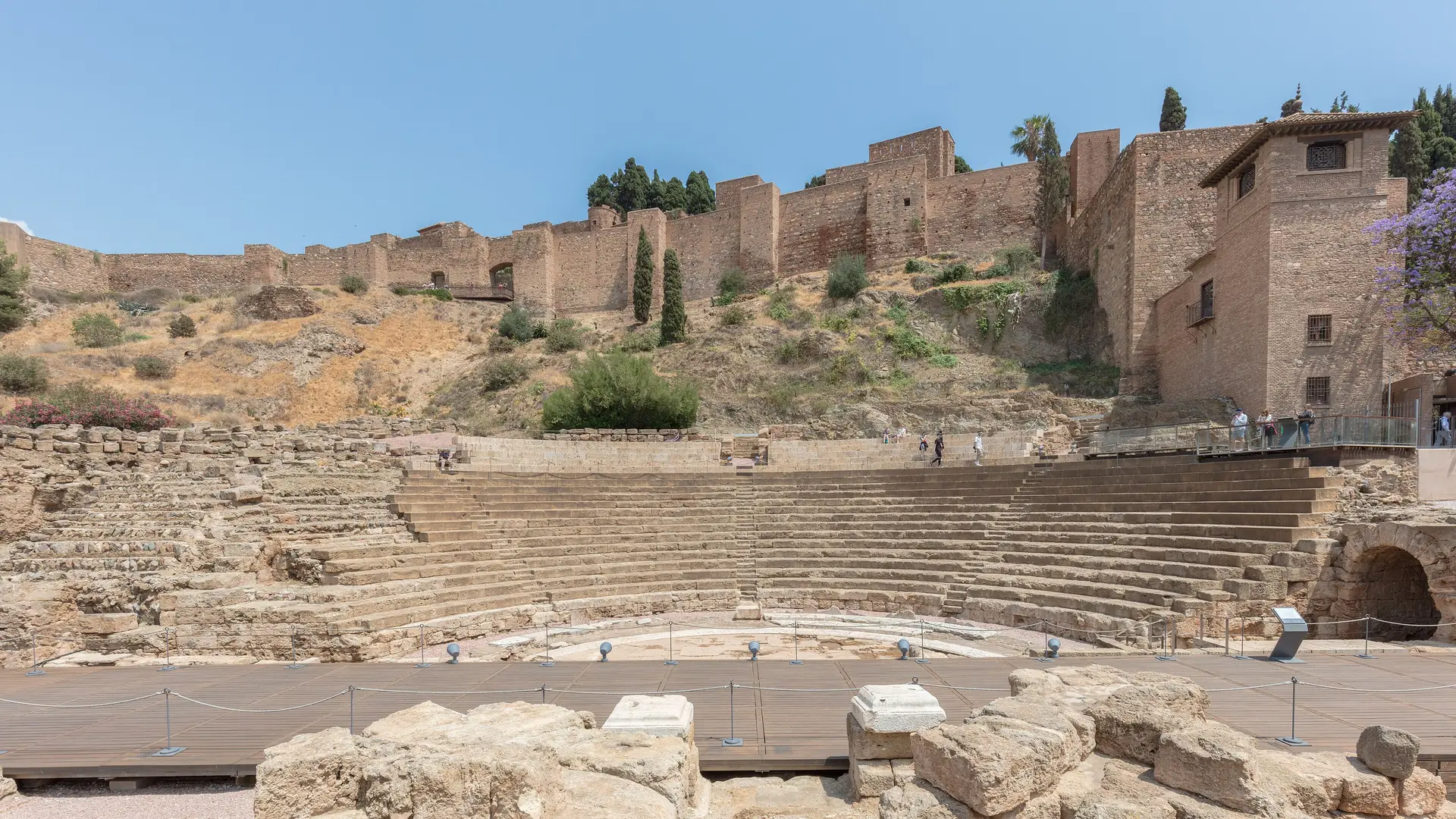 The stone seating tiers of the Roman Theatre of Malaga with the walls of the Alcazaba fortress rising on the hillside above
