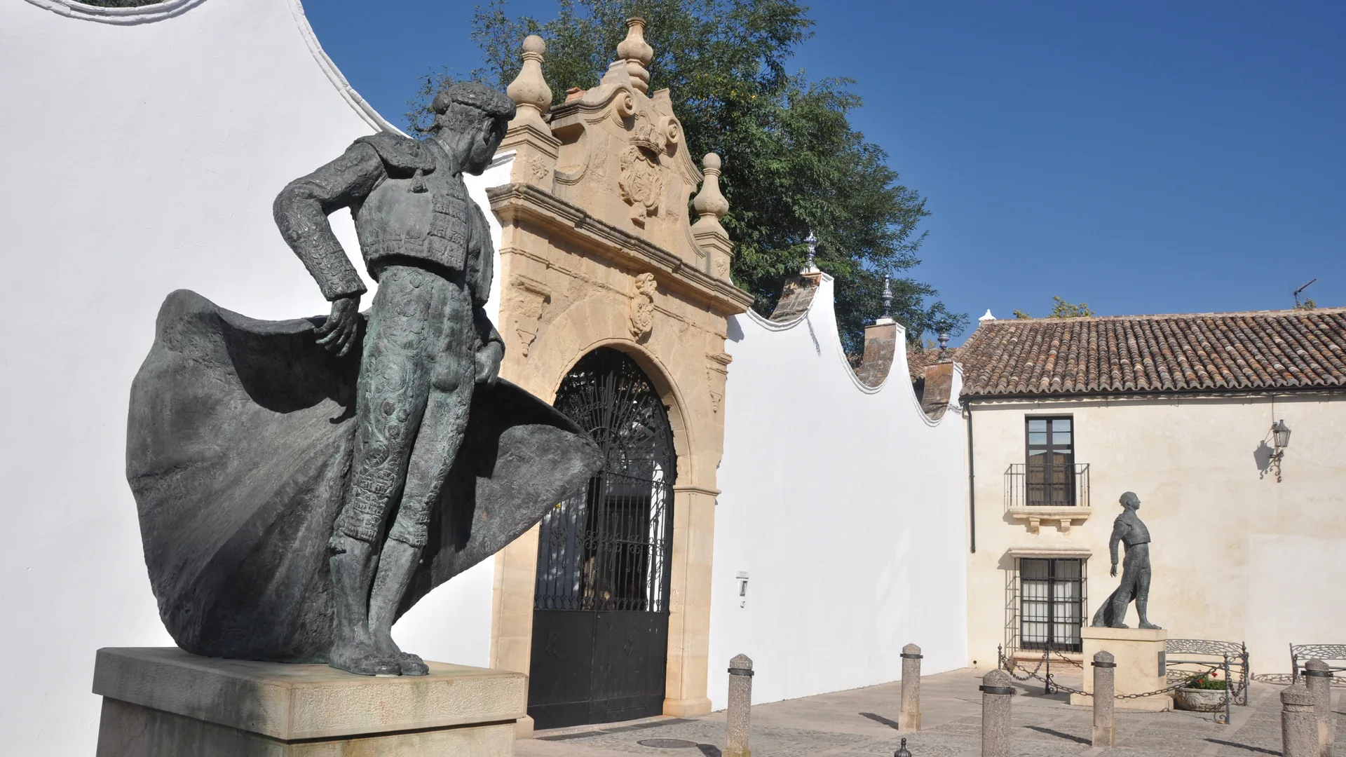The entrance gate of the Real Maestranza bullring in Ronda, with matador statues in the courtyard