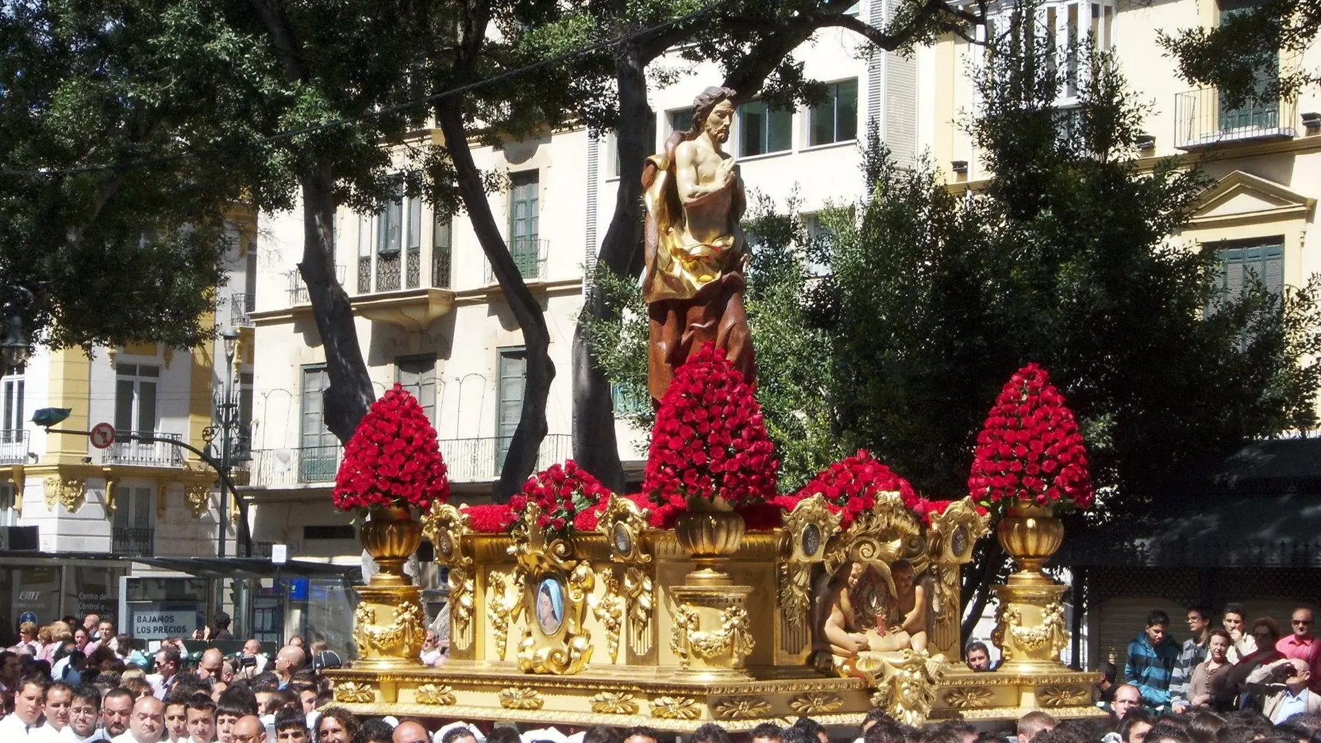 A Holy Week procession in Málaga with a decorated throne carried through the streets