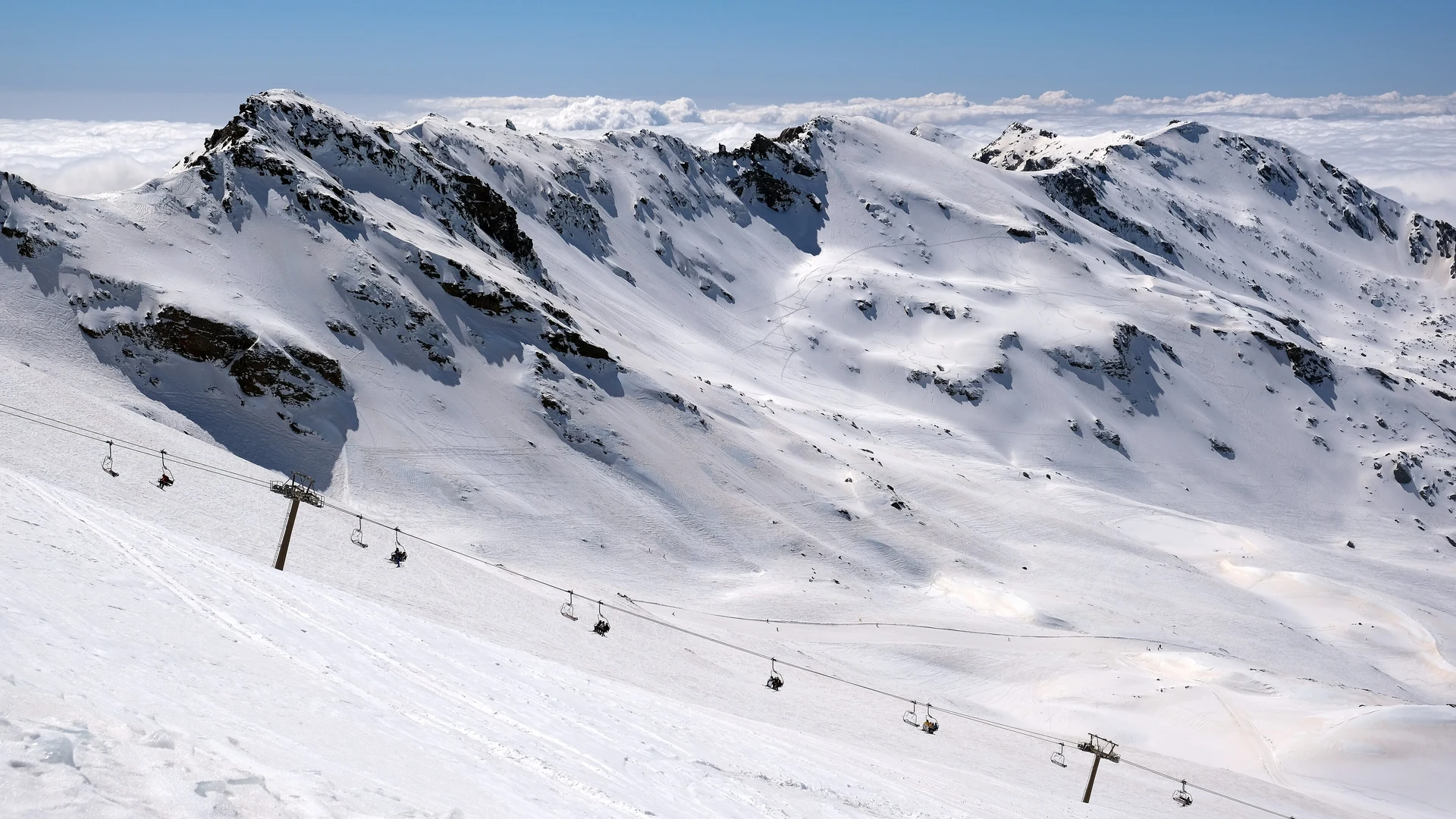 Snow-covered peaks of the Sierra Nevada mountain range in southern Spain under a clear blue sky