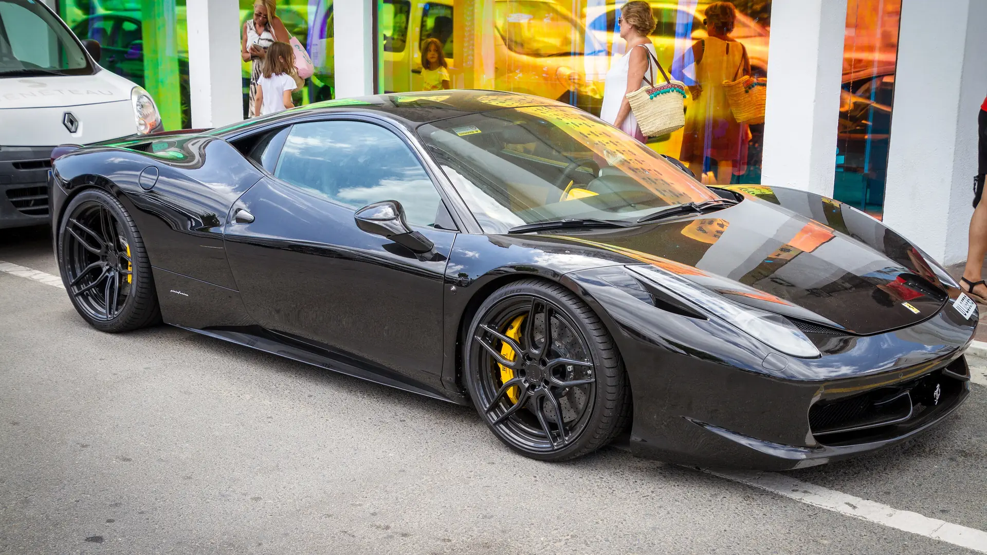 A black Ferrari sports car parked on a street in Puerto Banús, Marbella