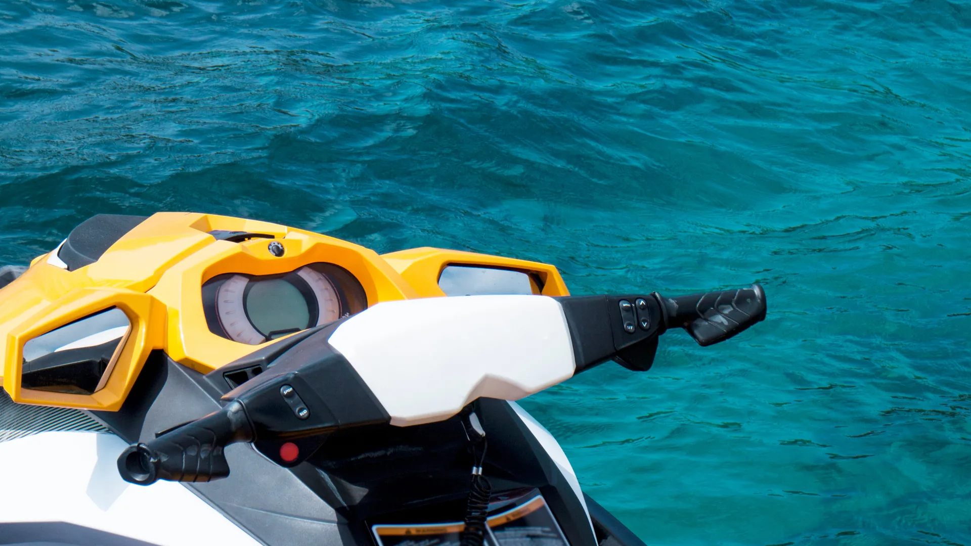 Close-up of a yellow and white jet ski on turquoise sea water, a popular water sports activity for tourists