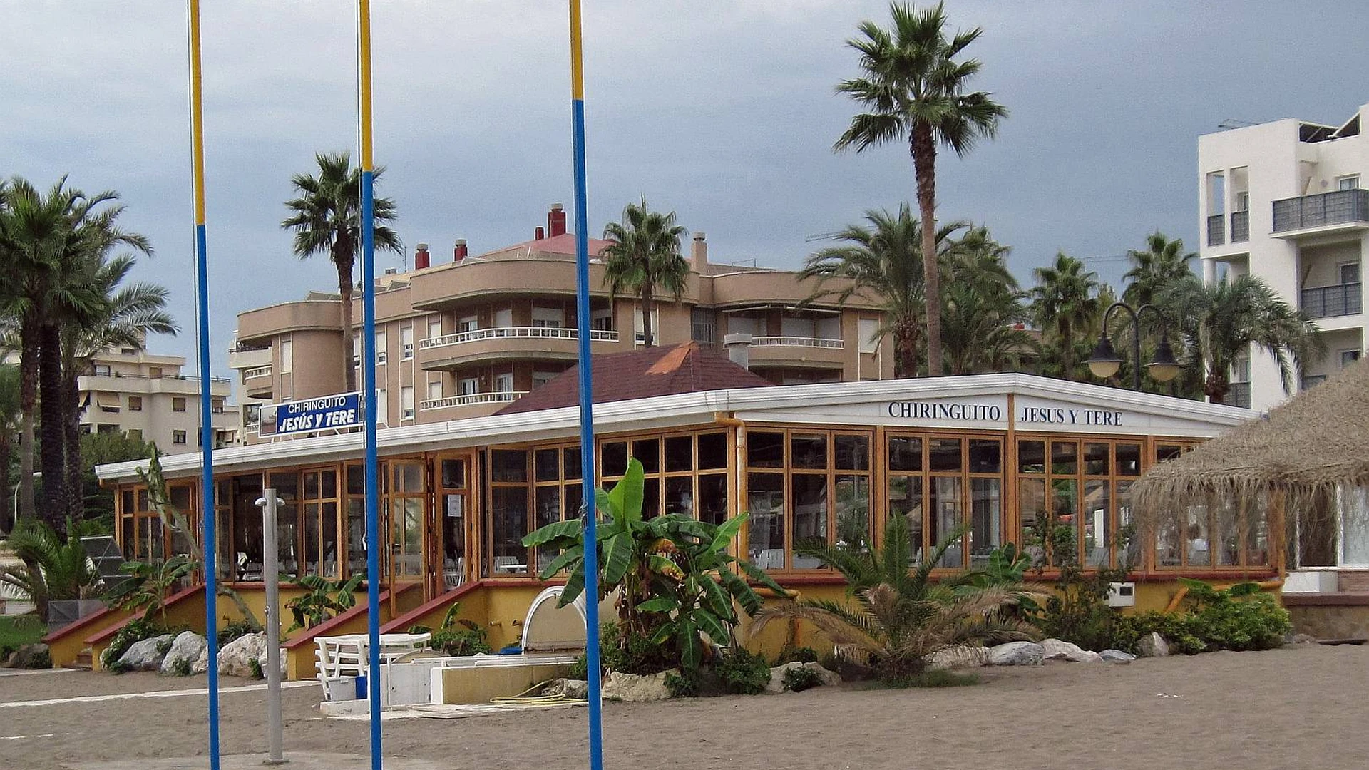 A beach chiringuito building on the sand at Torremolinos with palm trees behind