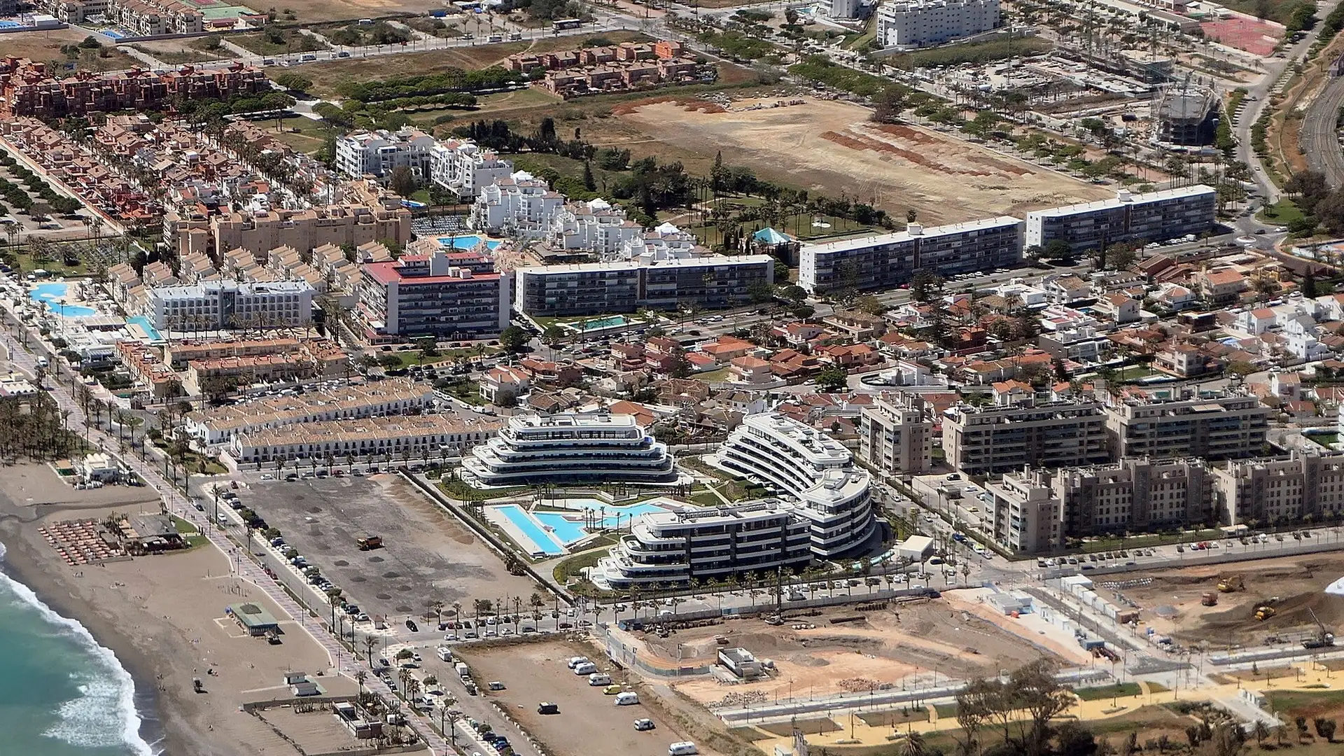 Aerial view of seafront hotel complexes with swimming pools beside the beach at Los Álamos in Torremolinos