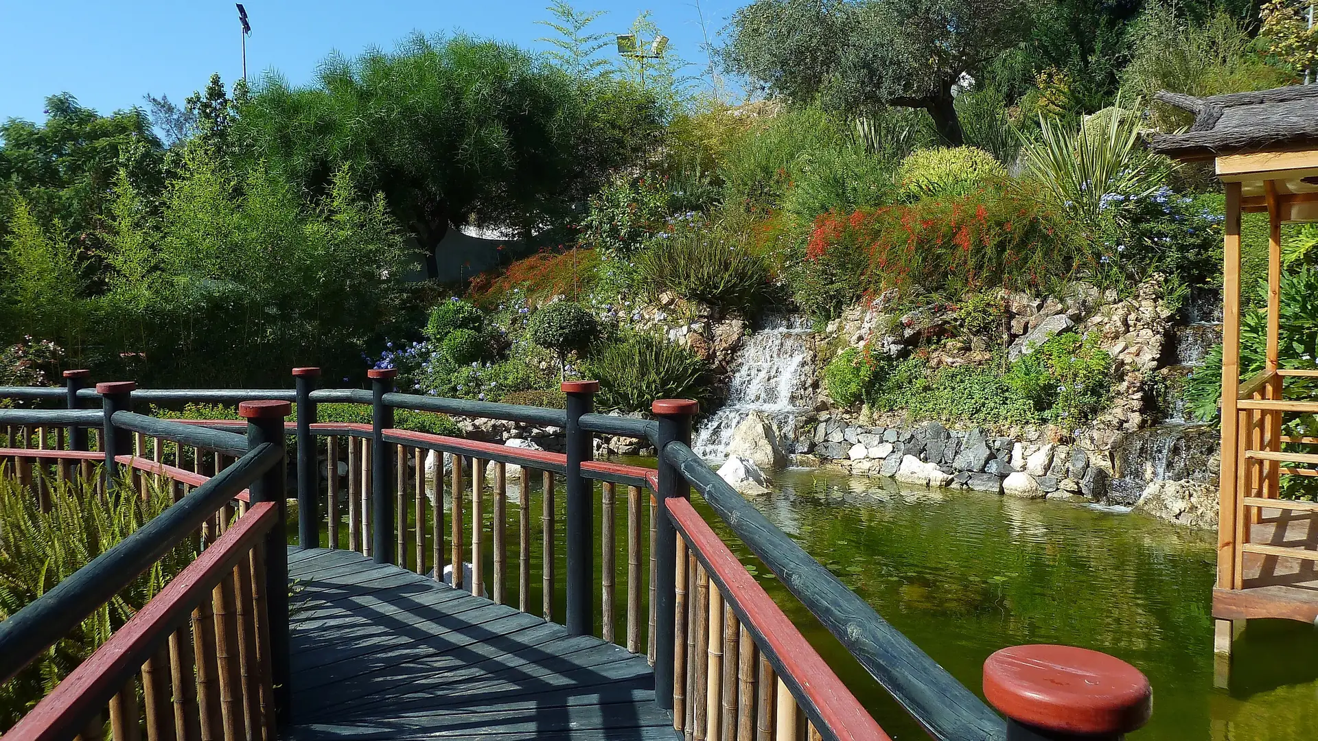 Wooden bridge, pond and waterfall in the Japanese garden of the Molino de Inca botanical garden in Torremolinos