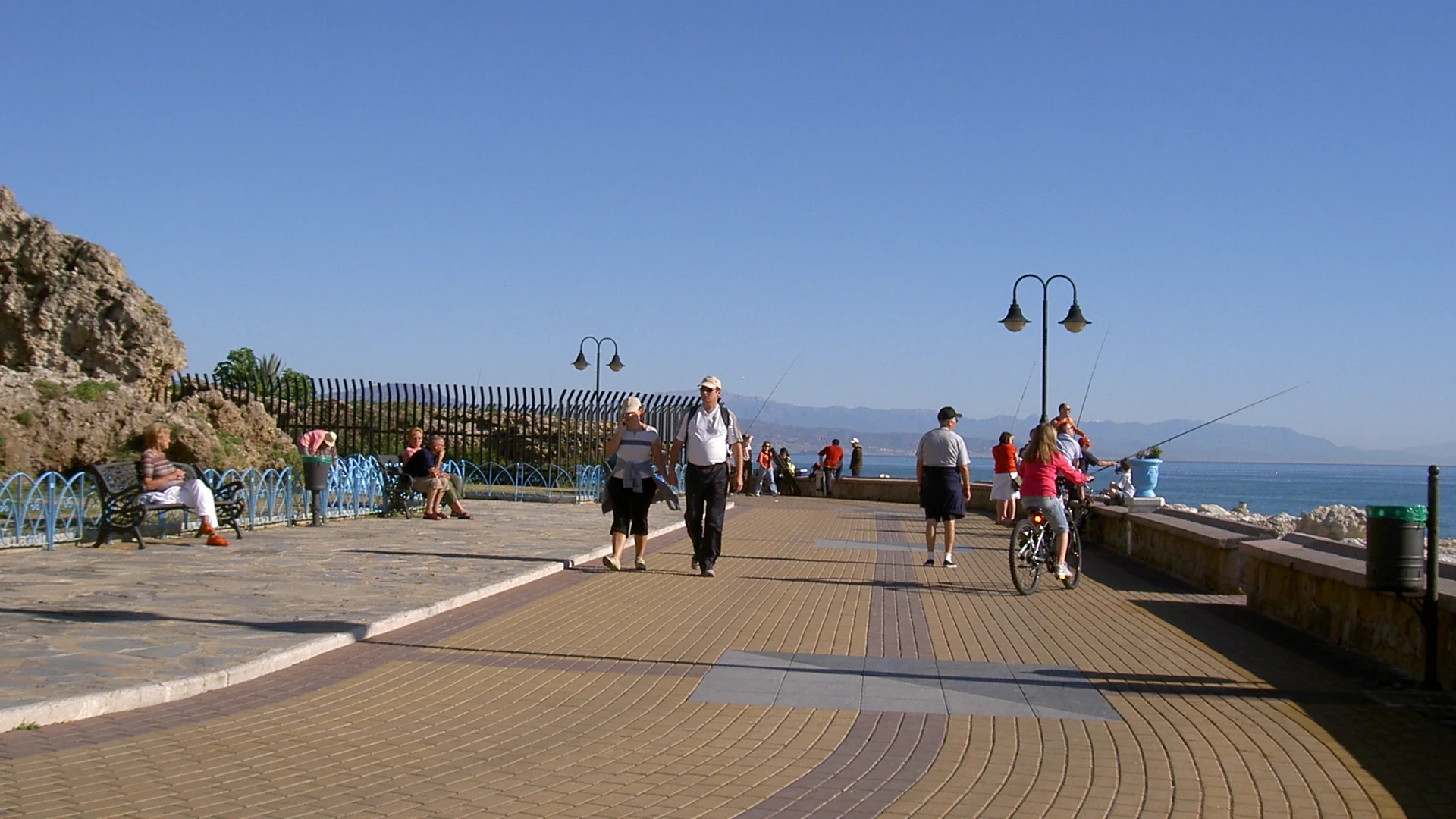 Walkers and a cyclist on the Torremolinos seafront promenade beside the sea