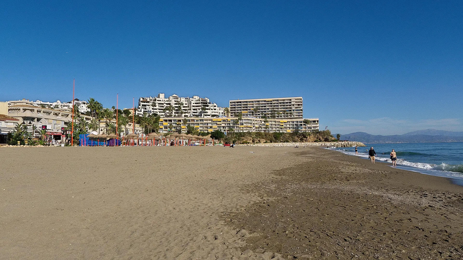 Wide sandy beach under a blue sky at La Carihuela in Torremolinos