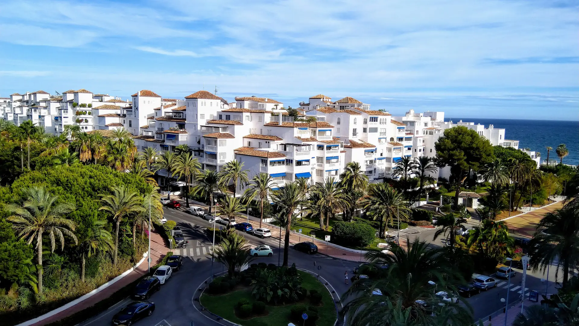 Whitewashed residential complexes and palm-lined streets in Nueva Andalucía, Marbella