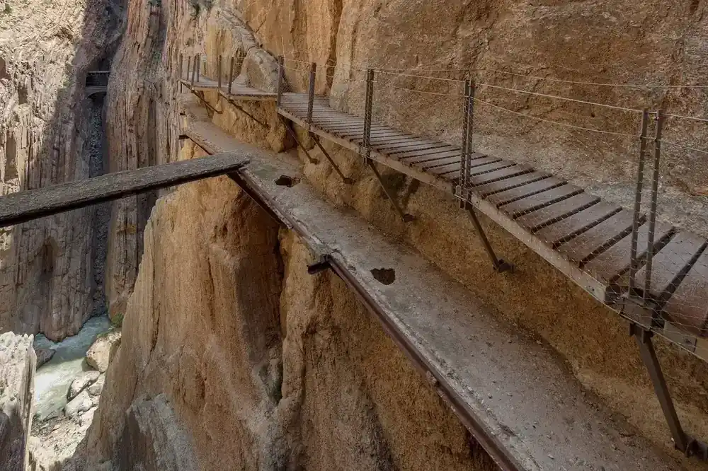The crumbling original 1905 walkway clinging to the cliff, with the modern boardwalk running above it