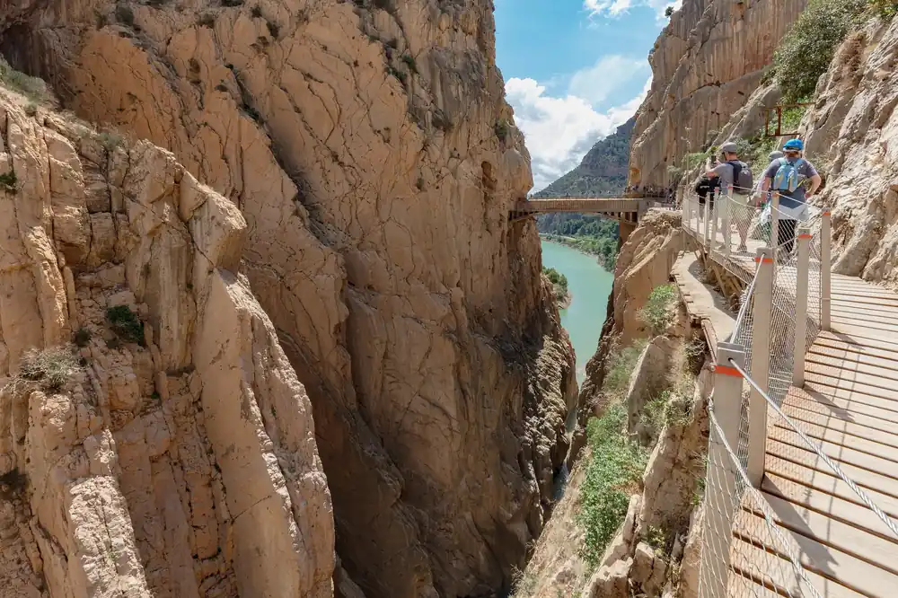 Walkers on the Caminito del Rey boardwalk bolted to a cliff above the turquoise Guadalhorce river