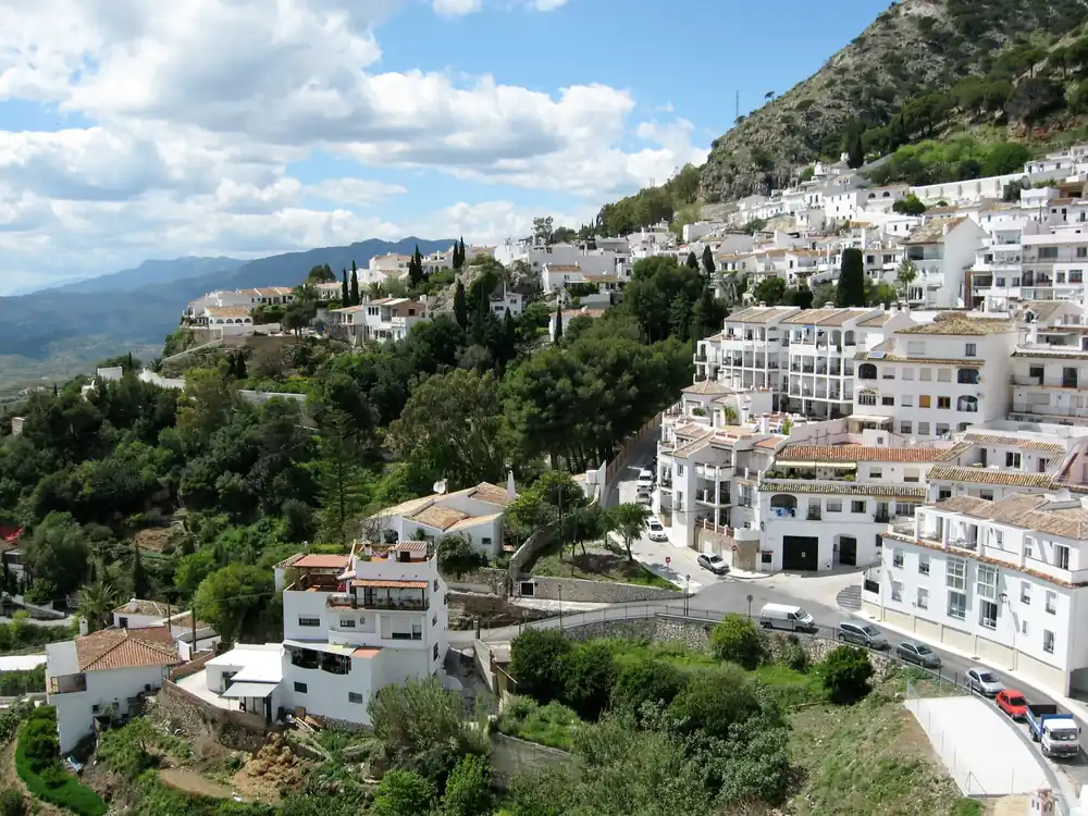 The whitewashed houses of Mijas Pueblo spread across a green hillside
