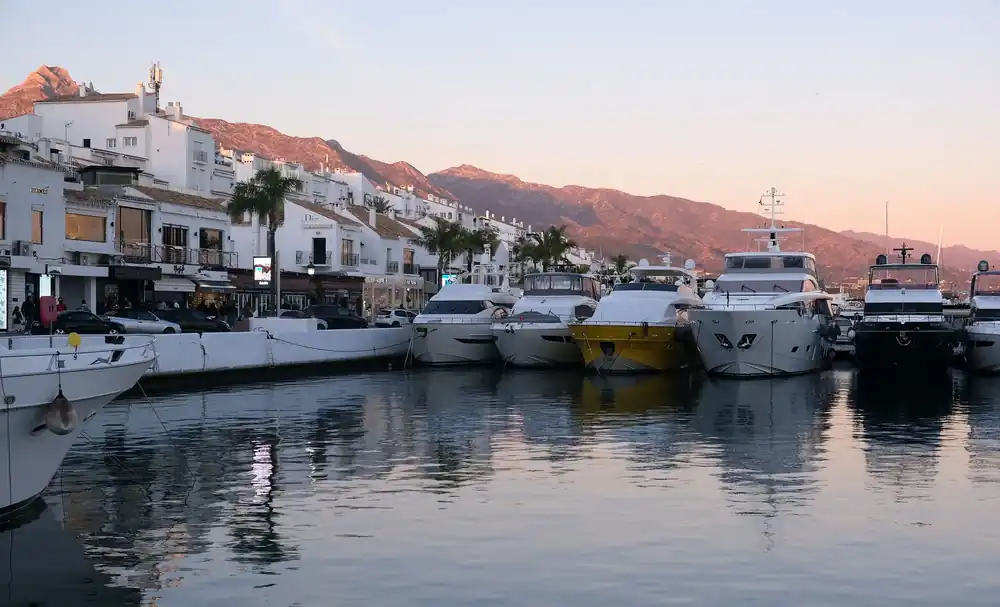 Yachts moored in Puerto Banús marina at dusk with the mountains behind Marbella